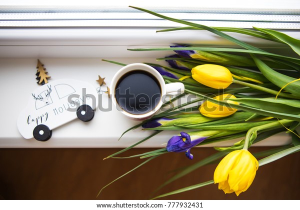 beautiful flowers-tulips and irises\
lie on the windowsill with a typewriter and a Christmas\
tree.