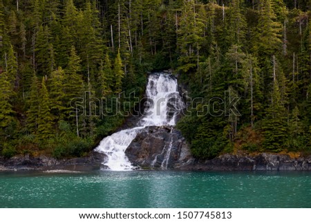 Beautiful flowing waterfall into the ocean in Endicott Arm fjord near Juneau Alaska