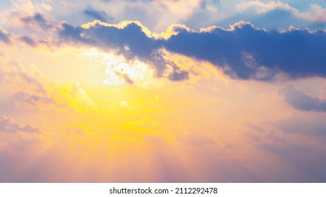 Beautiful fluffy clouds and rays of sunshine painted in bright painterly colors at sunset. Multicolor background or wallpaper