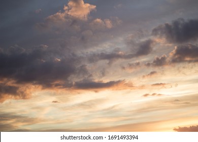 Beautiful fluffy clouds at sunset. Bright saturated yellow-orange and peach color of the sky. Summer sky.