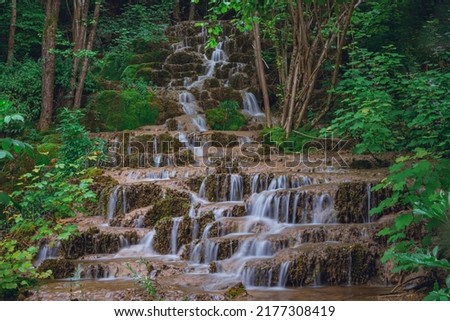 Beautiful forest and cascade stream with silky motion blurred water. Long exposure view of Bigar waterfall in eastern Serbia during summer.	
