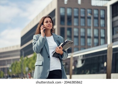 Beautiful Formal Dressed Business Woman In Suit With A Laptop And Notebook Outdoor. Brunette Caucasian Female, Standing Near Office.