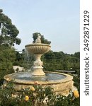 Beautiful fountain in the Parque Retiro surrounded by yellow and pink flowers 