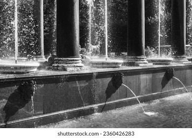 Beautiful fountain water splashes in the park. Fragment of ancient architectural composition.