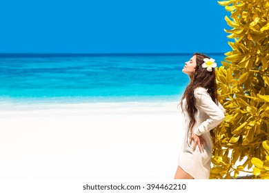 Beautiful Free Woman Enjoying On Exotic Beach In Summer By Tropical Blue Water. Attractive Girl With Long Hair Sunbathing And Resting, Outdoor Portrait. Bliss Freedom Concept. Travel.