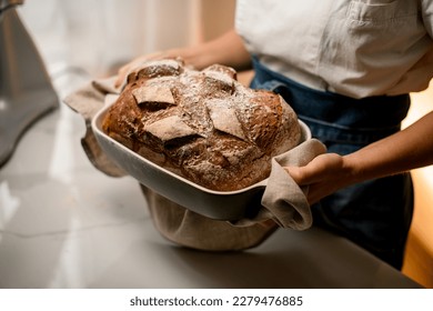 beautiful freshly baked sourdough bread in bakery form which female hands holds. Homemade bread food photography. Cropped photo - Powered by Shutterstock