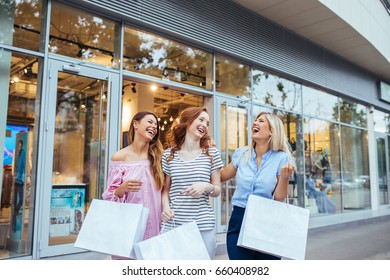 A Beautiful Friends Carrying Shopping Bags While Leaving The Store.