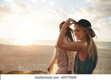 Beautiful friends enjoying a walk on the beach on a sunny day. Two young women walking together on a beach.