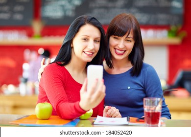 beautiful friends taking a self portrait with phone in cafe