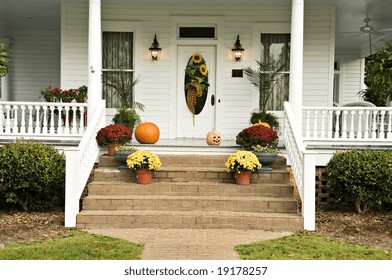 A Beautiful Front Porch Decorated For Fall With Sunflowers, Mums, Pumpkins, Pansies, And A Jack-o-latern