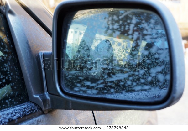 beautiful frosty patterns in the rearview mirror on\
the glass of the car