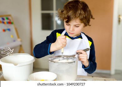 Beautiful Funny Blond Little Kid Boy Baking Chocolate Cake And Tasting Dough In Domestic Kitchen