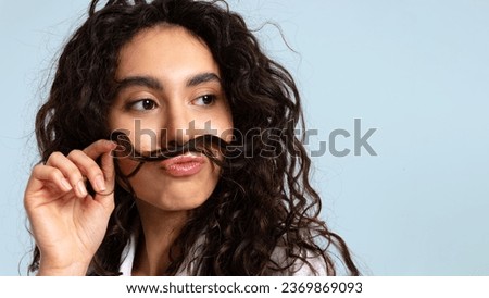 Beautiful funny girl fooling around making a mustache out of her long dark hair