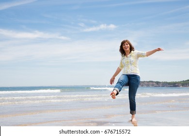 Beautiful And Funny Middle Aged Woman Splashing Water With Foot On The Seashore