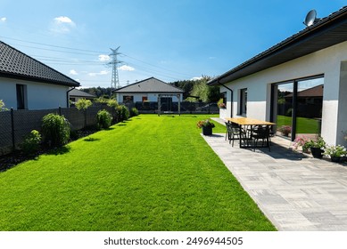 Beautiful garden with green grass, visible terrace table and house in beautiful summer weather, very wide shot. - Powered by Shutterstock