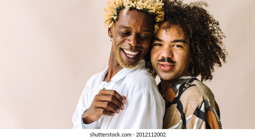 Beautiful Gay Couple Standing Next To Each Other In A Studio. Two Young Male Lovers Posing Together Against A Studio Background. Happy Young Gay Couple Smiling Cheerfully.