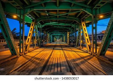 Beautiful Gdanski Bridge By Night In Warsaw, Poland, Steel Truss Construction With Tram Tracks, City Infrastructure, Vanishing Point Perspective.