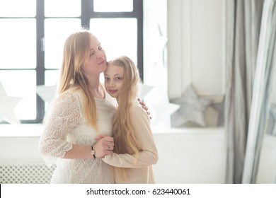 Beautiful Gentle Mom And Daughter Teenager With Long Blond Hair, Light Style And Hugs, Lifestyle, Real Interior