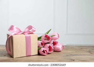 Beautiful gift box with bow and pink tulips on wooden table. Space for text - Powered by Shutterstock