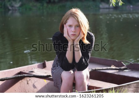 Beautiful ginger girl sitting sad in a rusty boat