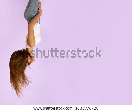 Beautiful girl 19 years old on pink background in jeans and light T-shirt, long flying hair, closed eyes. Upside down view. Concept of inspiration, dreams. Great photo for advertising. Copy space