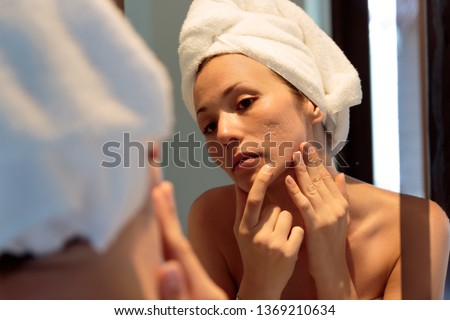 beautiful girl with acne looking herself on the mirror