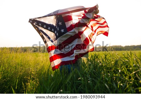 Beautiful girl with the American flag in a wheat field. 4th of July. Independence Day