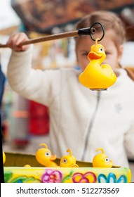 Beautiful girl in the amusement park to catch a toy duckling. Duck in focus.