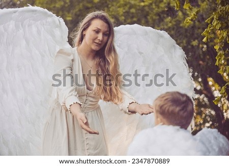 Beautiful girl angel with her son in the evening garden