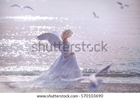 beautiful girl with angel wings is walking along the seashore