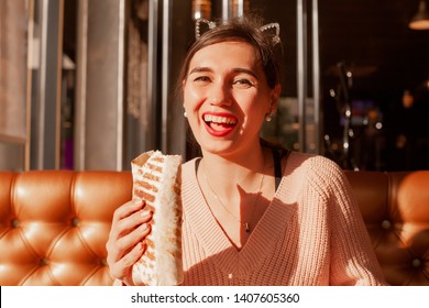 Beautiful Girl With An Appetite Eating A Burrito In The Cafe