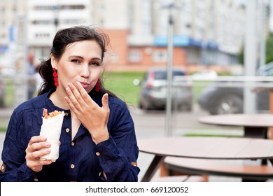 Beautiful Girl With An Appetite Eating A Burrito On The Street