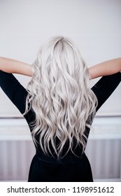 beautiful girl back with silver grey ash blonde curly wavy long hair in black dress isolated