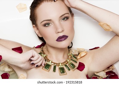 beautiful girl in a bath with flower petals, perfect makeup and jewelry