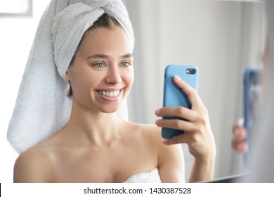 Beautiful Girl In The Bathroom Makes Selfie In The Mirror And Smiling