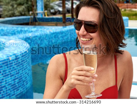 Beautiful girl in bikini drinking champagne at the pool