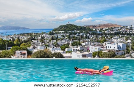 Beautiful girl in bikini lying on air bed swimming at pool - Typical Aegean (House) architecture in Bodrum, Turkey