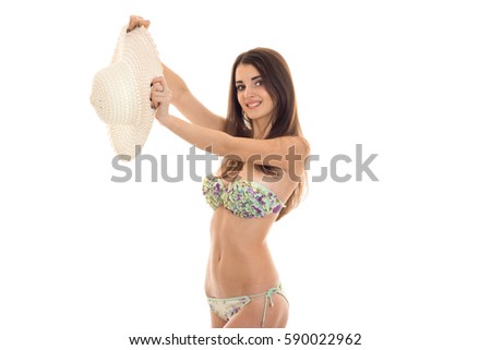 beautiful girl in bikini smiling and holding a hat isolated on white background