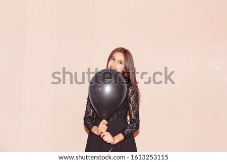 beautiful girl in black dress holds air balloon. valentines day, birthday, halloween, black friday, womens day, anniversary, holiday celebration concept