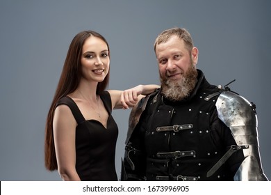 Beautiful girl in a black dress next to a knight in armor