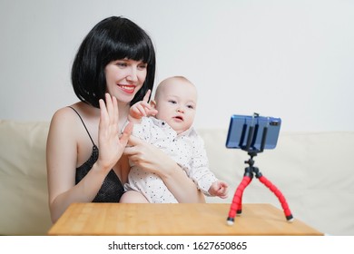 A Beautiful Girl Blogger With A Child Leads A Live Broadcast. Mommy Blogger With A Baby Records A Video For A Blog On A Smartphone