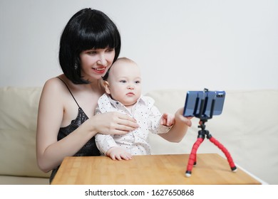 A Beautiful Girl Blogger With A Child Leads A Live Broadcast. Mommy Blogger With A Baby Records A Video For A Blog On A Smartphone