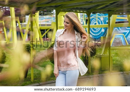 Beautiful girl blonde posing in the amusement Park