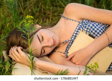 Beautiful Girl With A Book Fell Asleep On A Green Meadow