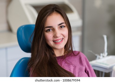Beautiful girl with braces smiles in dentistry.