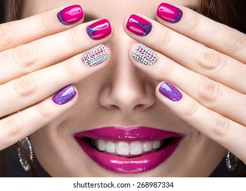 Beautiful girl with a bright evening make-up and pink manicure with rhinestones. Nail design. Beauty face. Picture taken in the studio on a black background.