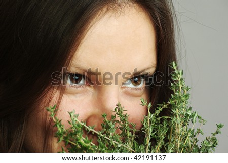 Beautiful girl with bright eyes sniffing thyme