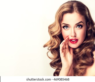 Beautiful girl with bright makeup and curly hair   telling a secret .Portrait  young happy woman who is calling to someone .Funny girl model  whispering about something. Expressive facial expressions
