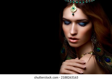 Beautiful girl with bright make-up, jewelery peacock feather earrings, diadem and manicure. Sensual east look