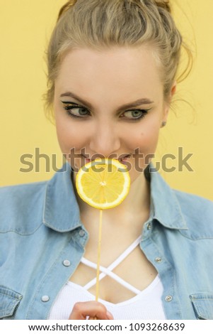 beautiful girl with bright yellow makeup. Holds the lemon as a lollipop.